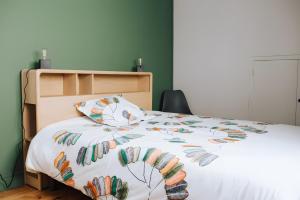 a bed with a white comforter with feathers on it at Le nid du Randonneur in Marmanhac