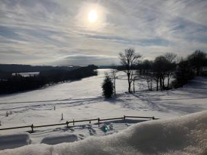 a snow covered field with the sun in the sky at Le nid du Randonneur in Marmanhac
