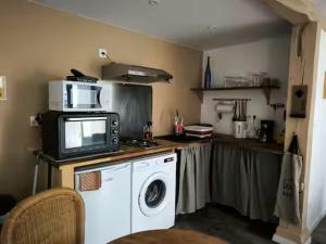 a kitchen with a microwave and a washing machine at Limousin, Saint Vitte sur Briance Vacances au Mazet de Nova in Martageix