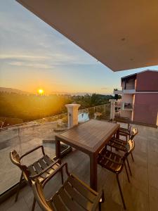 a wooden table and chairs on a balcony with the sunset at Thomas Apartments in Dassia