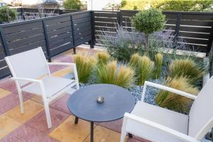 a patio with white chairs and a table and plants at Magisto Loft in Nea Moudania