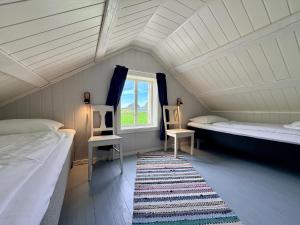 a attic room with two beds and a window at The Haukland House, Between Peaks & Sea in Leknes