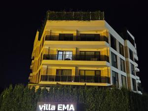 a tall yellow building at night at Beach apartments Ema in Kranevo