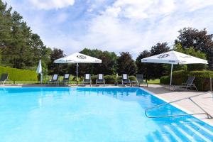 ein großer Swimmingpool mit Sonnenschirmen und Liegestühlen in der Unterkunft Hotel Ottenstein - Das Wohlfühlhotel in Rastenfeld