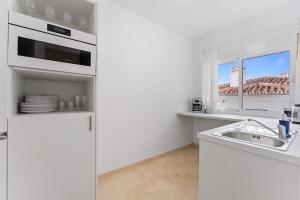 a white kitchen with a sink and a window at Edf España Suites Mijas in Mijas