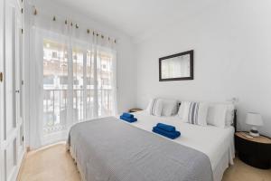 a white bedroom with a large bed with blue towels on it at Edf España Suites Mijas in Mijas