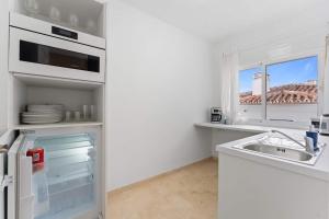 a white kitchen with a sink and a window at Edf España Suites Mijas in Mijas
