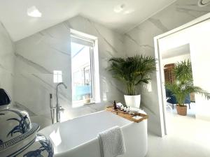 a white tub in a bathroom with plants at Doleen Quay House in Ballyconneely +144 photos