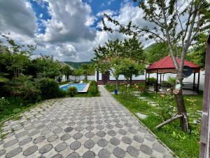 a stone walkway with a gazebo and a swimming pool at Gabala White House in Gabala