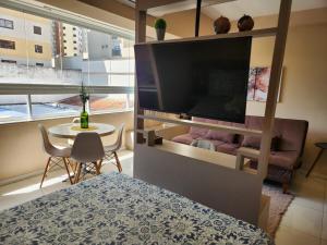 a room with a bed and a tv and a table at Lindo Studio no Centro de Poços de Caldas in Poços de Caldas