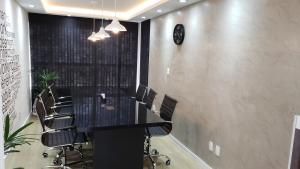 a conference room with a long black table and chairs at Lindo Studio no Centro de Poços de Caldas in Poços de Caldas