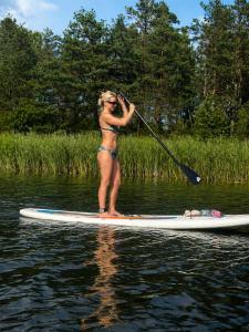 a woman in a bikini standing on a paddle board at Karolio Sodyba Palūšėje in Palūšė