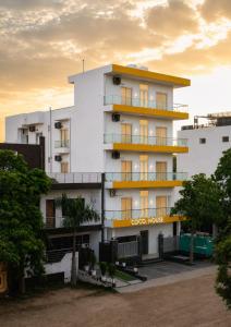 a white building with yellow balconies and trees at Coco House in Greater Noida