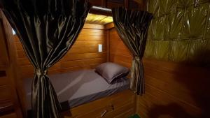 a small bed in a wooden room with curtains at Wonderful Hostel Trincomalee in Trincomalee