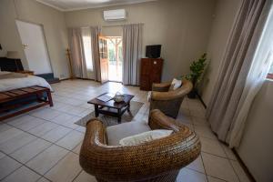 a living room with wicker chairs and a table at Beyond Cui Bono - Travel Addo Group in Sunland