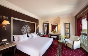 a hotel room with a large white bed and a chair at Sonesta St. George Hotel - Convention Center in Luxor