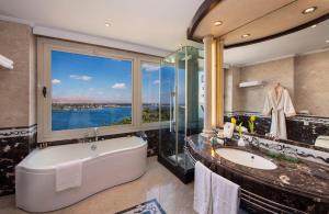 a bathroom with a large tub and a large window at Sonesta St. George Hotel - Convention Center in Luxor