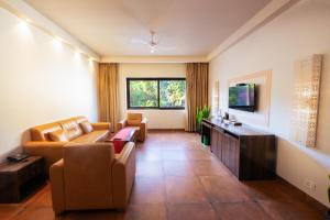 a living room with a couch and a tv at The Ivy Anjuna in Anjuna