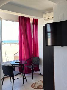 a living room with a table and red curtains at Hotel Azur in Costinesti