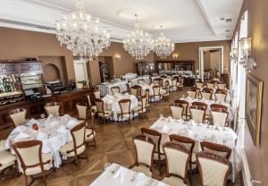a restaurant with white tables and chairs and chandeliers at Pałac Żelechów Spa & Wellness in Żelechów