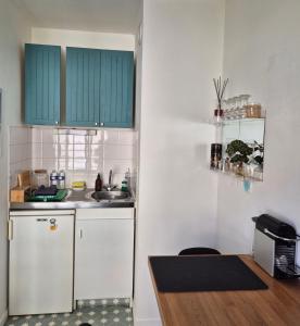 a kitchen with green cabinets and a white refrigerator at Villa Sévigné in Nantes