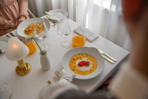 a table with a plate of food and glasses of orange juice at Wanda Luxury Boutique Hotel - tylko dla dorosłych in Szczawnica