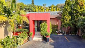a building with a red door and some trees and bushes at RAMATA GUEST HOUSE in Pretoria