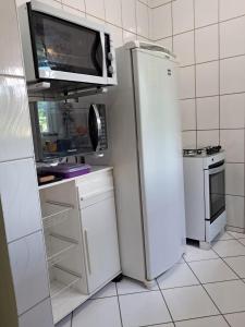 a white kitchen with a refrigerator and a microwave at Apartamento São Pedro SP in São Pedro