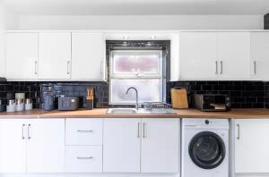 a white kitchen with a sink and a washing machine at Mauldeth Shared House in Manchester +38 photos