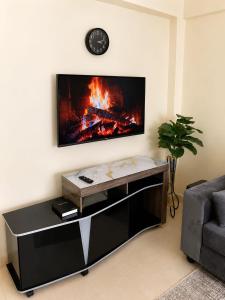 a living room with a fireplace and a tv on the wall at Fahari House in Embu +3 photos