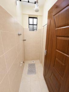 a bathroom with a shower with a wooden door at Fahari House in Embu