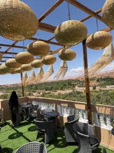 a woman sitting on a patio with chairs and chandeliers at Qamar Mgouna Hotel in El Kelaa des Mgouna
