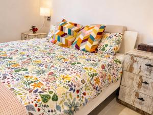 a bed with a colorful comforter and pillows on it at Casa Era Canaria in Arona +69 photos