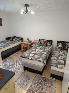 two beds in a room with a table and a dining room at Apartmani Konta in Livno