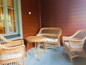 three wicker chairs and a table on a porch at Kärpänpesä B in Syöte