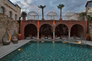 a swimming pool in a courtyard with chairs and a building at Elika Cave Suites Cappadocia, Curio Collection by Hilton in Ortahisar