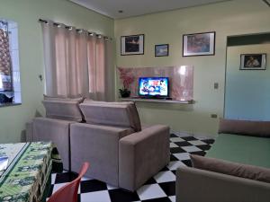 a living room with two chairs and a tv at Apartamento São Pedro SP in São Pedro