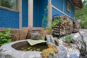a garden with a pond in front of a blue house at 高野神谷宿 一結 in Koyasan