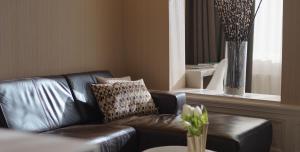 a black leather couch in a living room with a vase at Maurits Apartments & Suites in Rotterdam