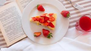 a piece of cake with strawberries on a plate next to a book at B&B Hotel Villa Nora in Bellaria-Igea Marina +32 photos