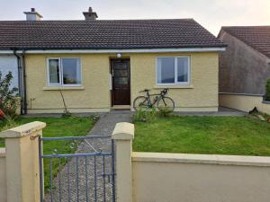 a yellow house with a bike parked in the yard at Sunrise House in Cahersiveen