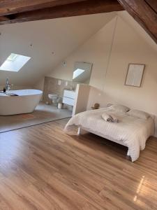 a bedroom with a large bed and a bath tub at Sous les combles in Hambach