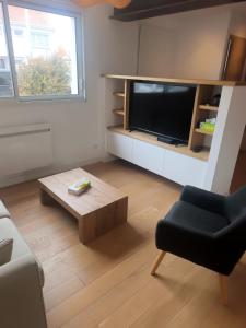a living room with a television and a coffee table at Maison près de la plage in Sangatte