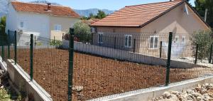 a fence in front of a house with a yard at Marija Holiday Home in Sućuraj