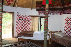 a bedroom with a bed in a room with a window at Happy Nomads - Modern Yurt Cottages & Breakfast in Karakol