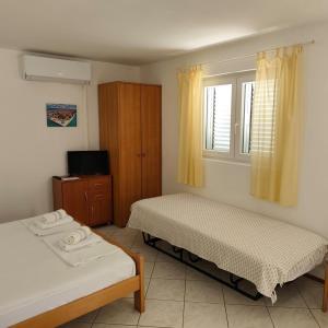 a bedroom with two beds and a television and a window at Apartments Ada in Primošten