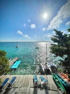 a dock with chairs and boats in the water at Cabañitas y Dorms in Bacalar