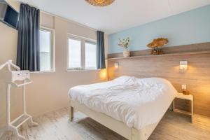 a bedroom with a white bed and a window at Appartementencomplex Juliana 148 in De Koog