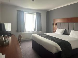 a bedroom with a bed and a desk and a window at Crossroads by Chef & Brewer Collection in Weedon Bec