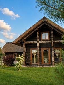 a log house with a large window on a lawn at KOPUVA seaside villas in Nida